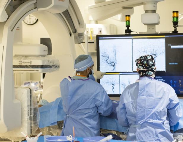 The backs of two neurosurgeons during procedure looking at monitors